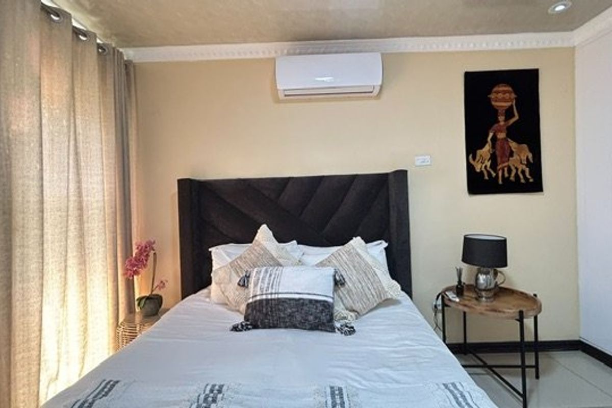 A well-maintained bedroom featuring a split-system air conditioner, built-in wardrobe, crown molding, and tiled flooring.