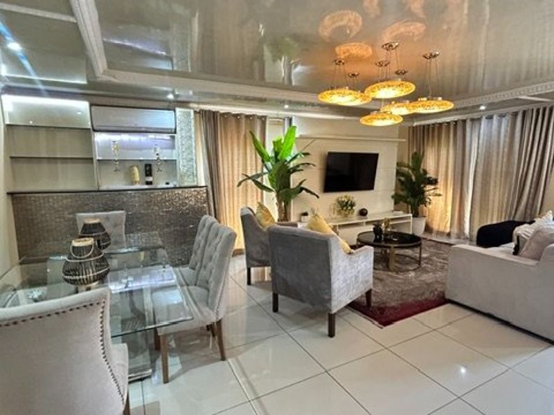 Spacious open-plan living and dining area featuring glossy ceilings, tiled flooring, a built-in bar counter, and integrated air conditioning.