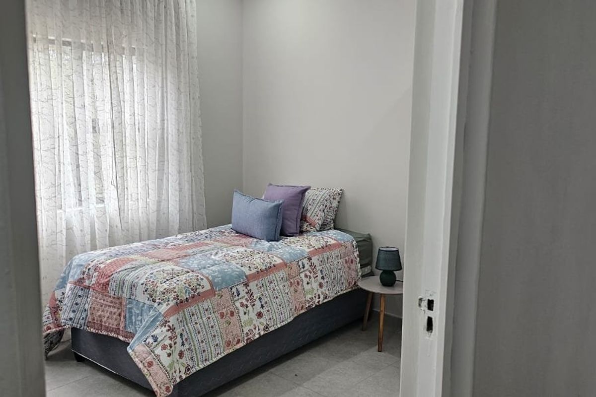 A well-lit bedroom featuring neutral wall finishes and tiled flooring, viewed from the doorway.
