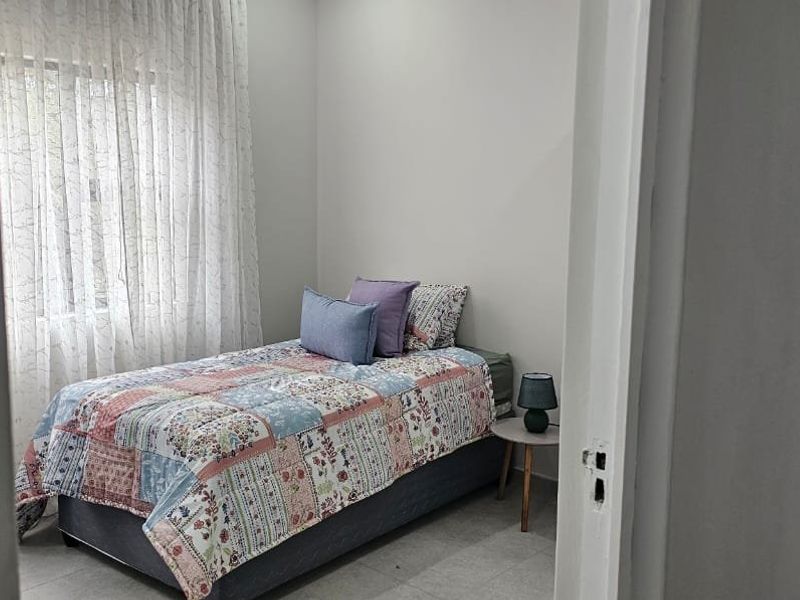 A well-lit bedroom featuring neutral wall finishes and tiled flooring, viewed from the doorway.