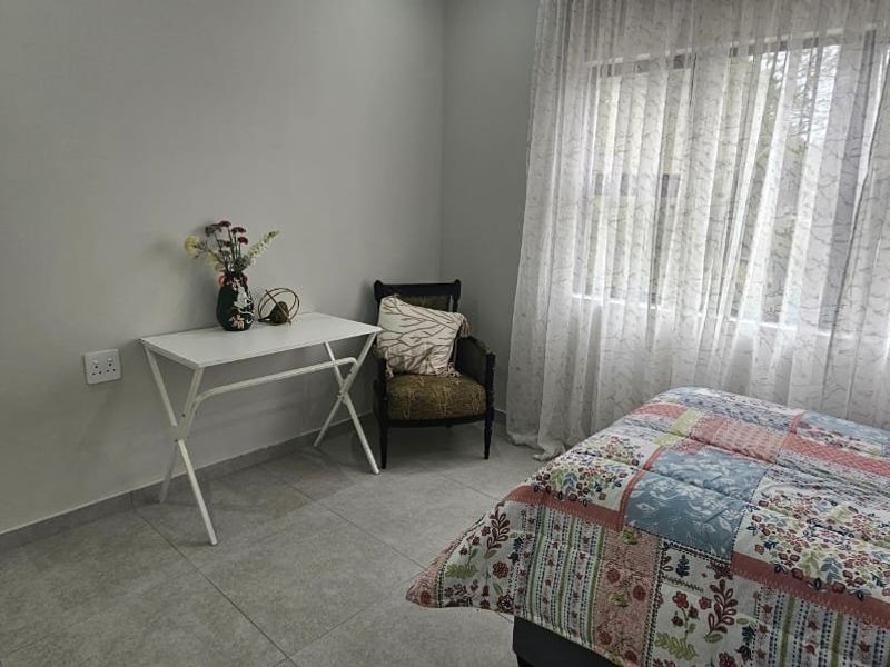 A well-lit bedroom featuring neutral wall tones and modern tiled flooring, providing a clean and functional space.