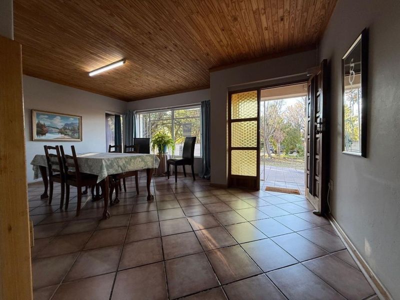 Spacious dining area featuring warm timber tongue and groove ceilings, ceramic tiled flooring, and direct access to the outdoor patio through a glass door.