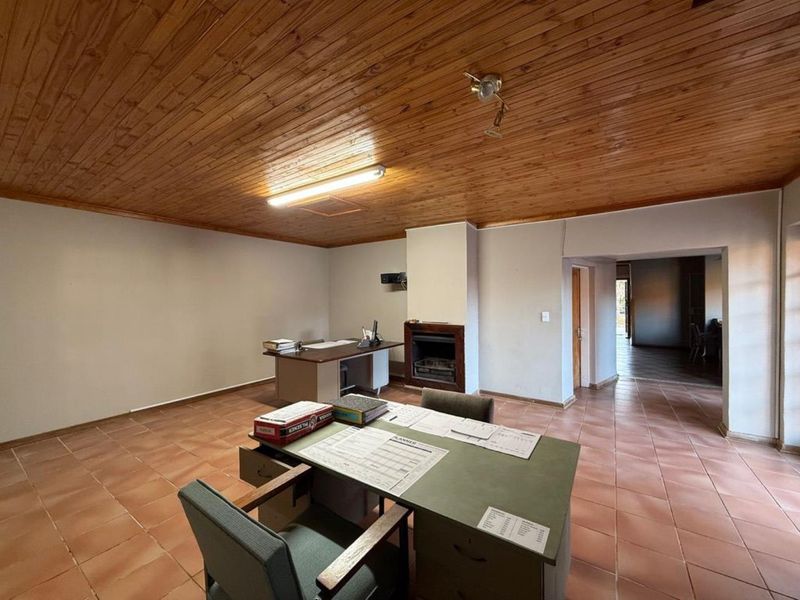 Spacious office area featuring a timber tongue and groove ceiling, ceramic tiled flooring, and a built-in fireplace.