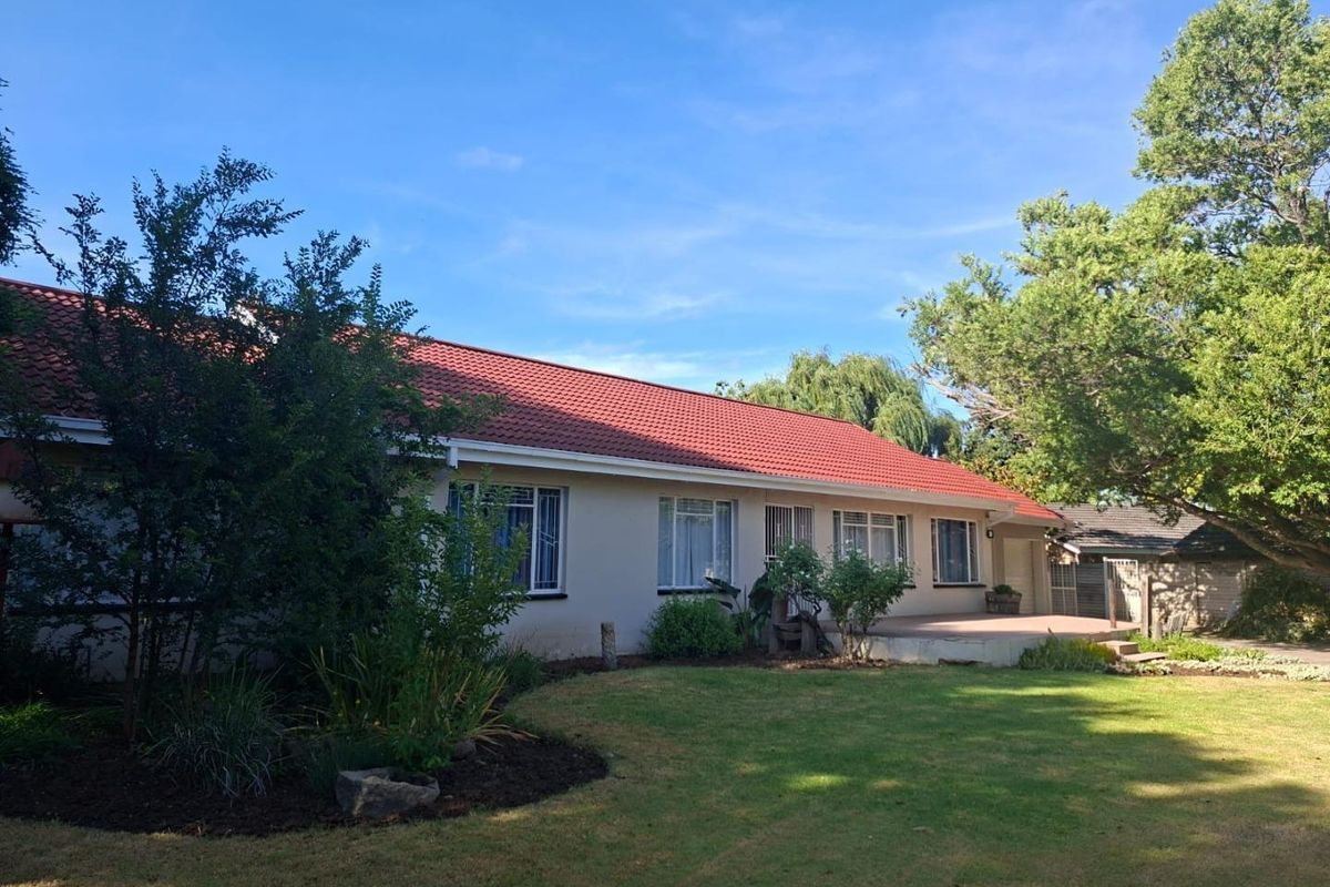 Rear view of the house featuring a tiled roof, a paved patio area, and a well-maintained garden.