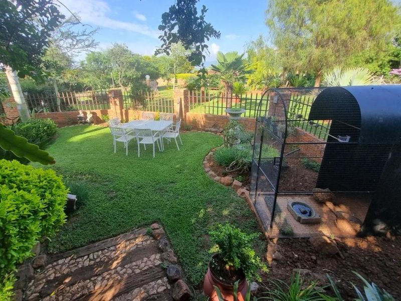 A well-maintained garden area featuring a manicured lawn, stone-paved pathway, and secure brick and metal perimeter fencing.