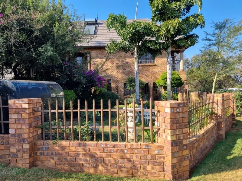 A two-story face brick commercial property featuring a secure perimeter with brick boundary walls, metal fencing, and an installed solar water heating system.