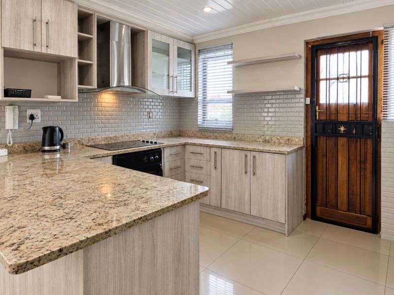 Modern kitchen featuring granite countertops, subway tile backsplash, built-in oven, electric cooktop, and timber-look cabinetry with direct access to the exterior.
