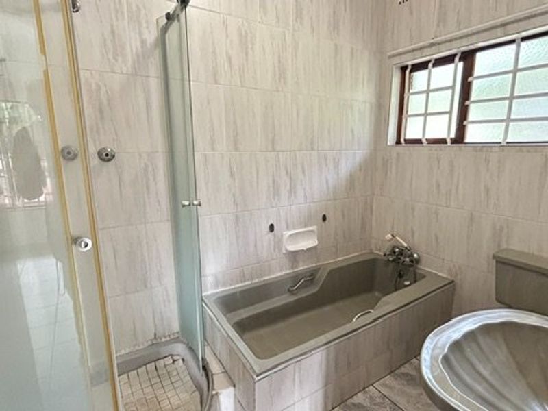 A functional bathroom featuring a built-in bathtub, separate shower enclosure, and tiled finishes, ready for a modern update.