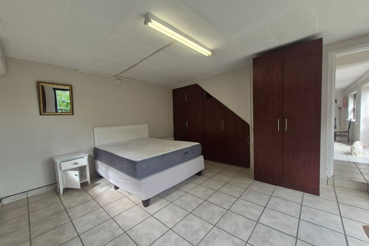 Spacious bedroom featuring built-in wooden cupboards, tiled flooring, and direct access to an adjacent hallway.