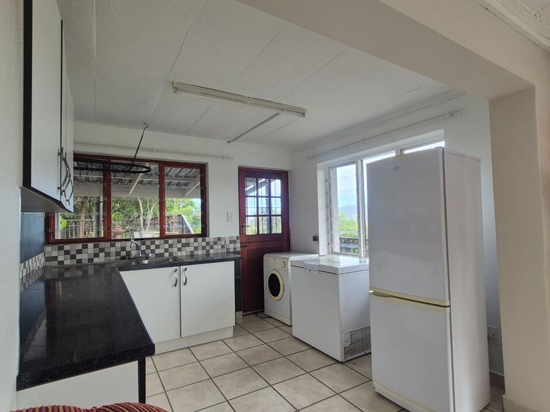 Functional kitchen featuring granite countertops, tiled backsplash, and direct access to the exterior, providing a practical layout for daily use.