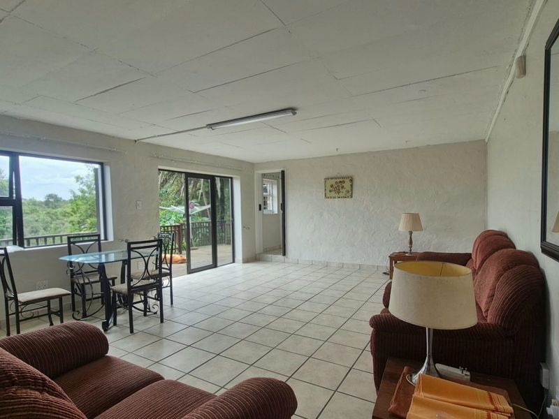 Open plan living and dining area featuring tiled floors, textured walls, and sliding glass doors leading to an outdoor patio space.