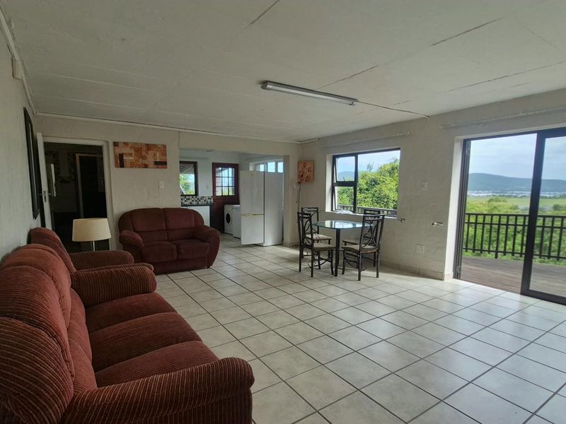 Spacious open-plan living and dining area featuring tiled floors, large windows, and direct access to a balcony with scenic views.