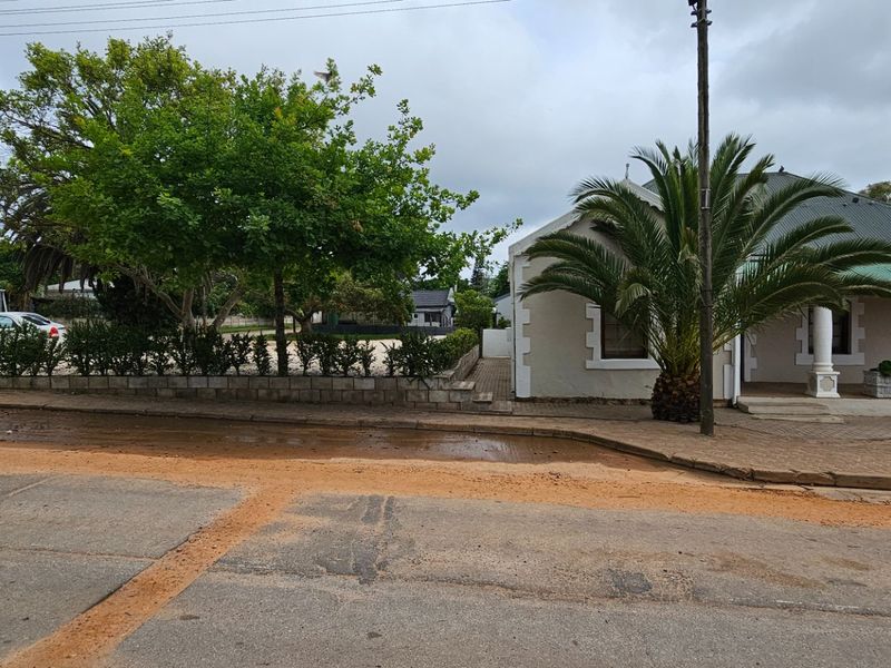 Front exterior view of a commercial property featuring a covered veranda with stone columns, paved driveway, and established garden landscaping.