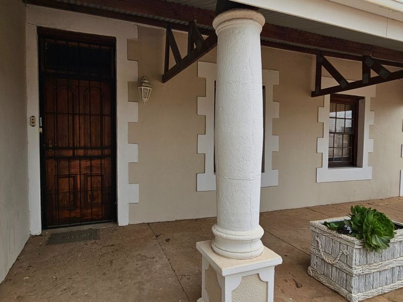 A covered veranda featuring decorative columns, timber roof trusses, and a secure entrance door, providing a classic exterior transition space.