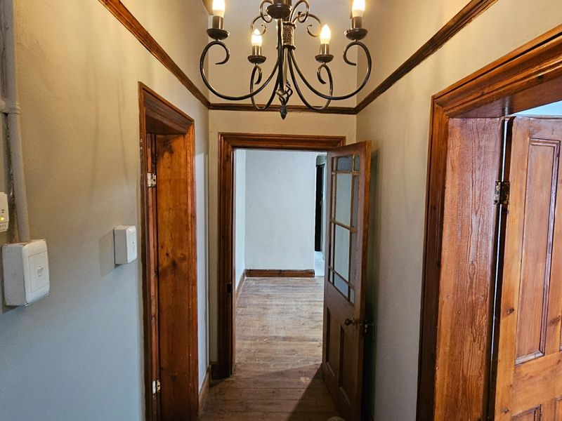 A functional hallway featuring timber door frames, original timber flooring, and classic picture rails, connecting multiple rooms within the commercial property.