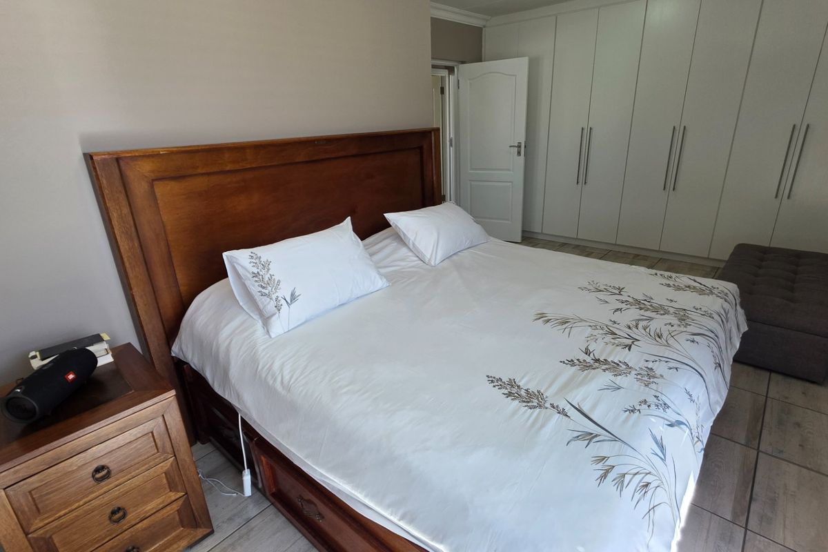 A well-maintained bedroom featuring neutral wall tones, tiled flooring, and extensive built-in cupboard storage.