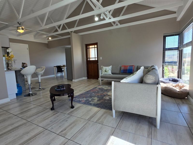 Spacious open-plan living area featuring high vaulted ceilings with exposed trusses, tiled flooring, and a functional kitchen island layout.