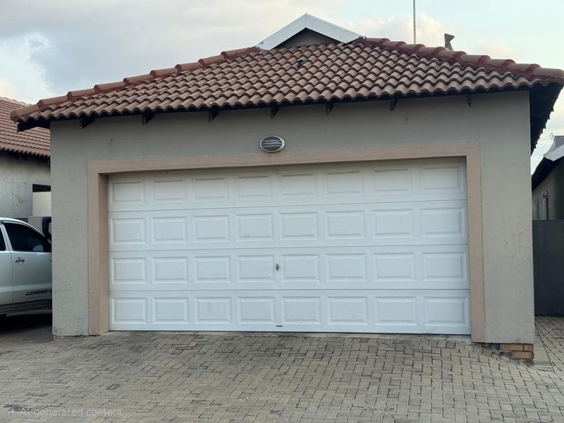 A well-maintained single garage featuring a white sectional door, tiled roof, and paved driveway access.