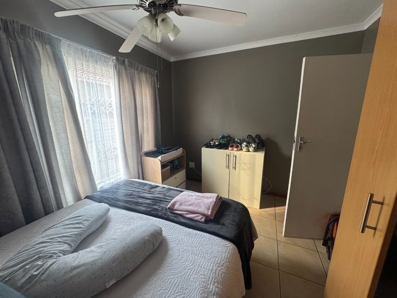 A functional bedroom featuring tiled flooring, a ceiling fan, and built-in storage, offering a neutral base for personalization.