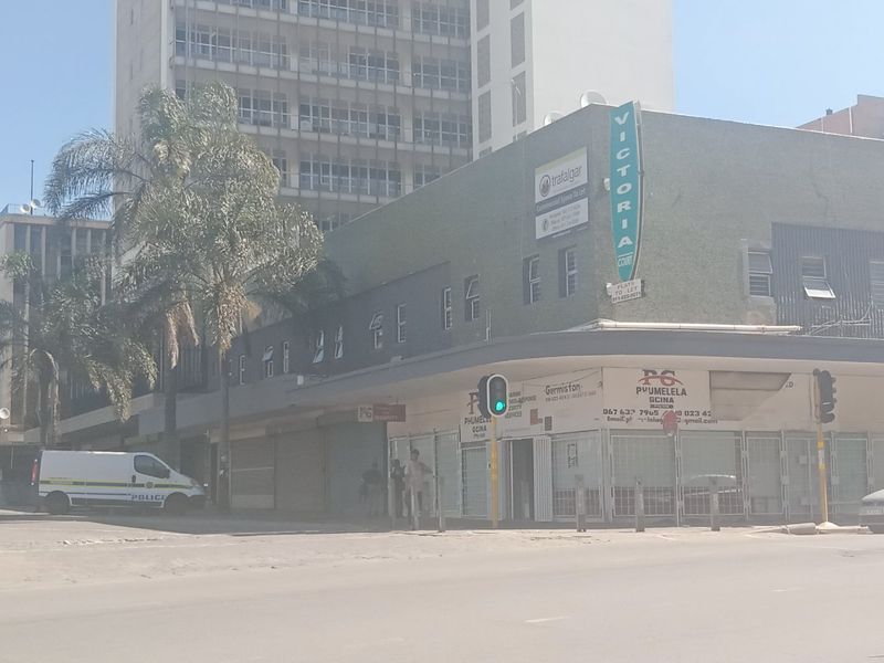 Street-level view of a commercial building featuring ground-floor retail spaces with security gates and upper-level office or residential units.