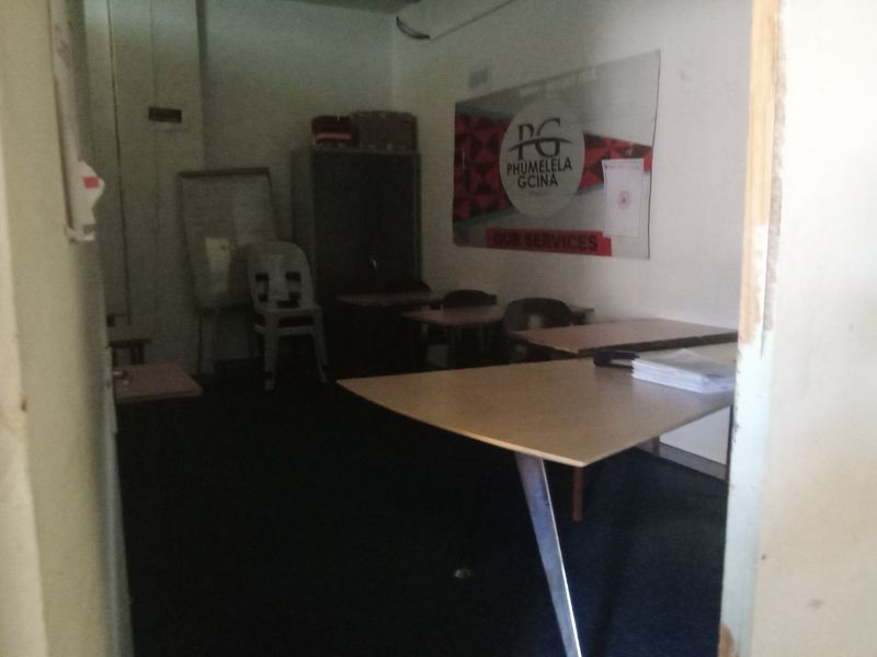 A small commercial office space featuring carpeted flooring and basic interior finishes, currently utilized as a workspace.