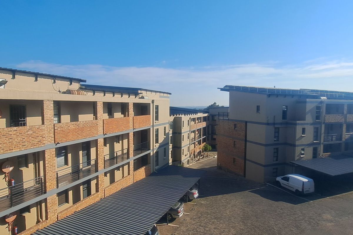 Aerial view of a modern townhouse complex featuring brick facades, covered parking bays, and solar panel installations on the roof.