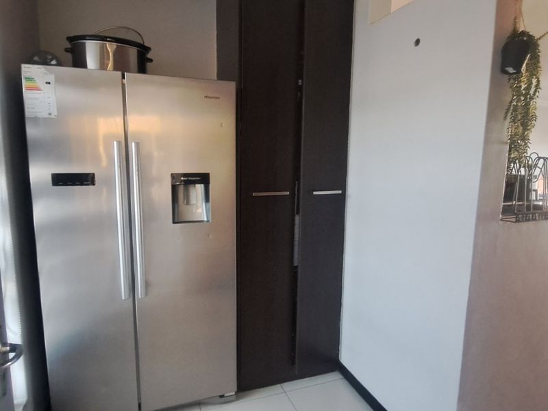 A kitchen area featuring built-in dark cabinetry and tiled flooring, with an open-plan layout leading into the adjacent living space.