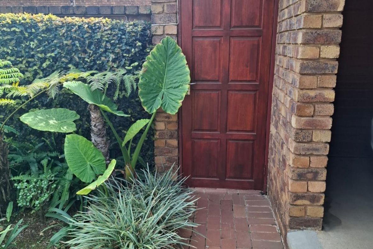 A side access area featuring a face brick wall, a solid timber door, and a brick paved pathway leading alongside the property.