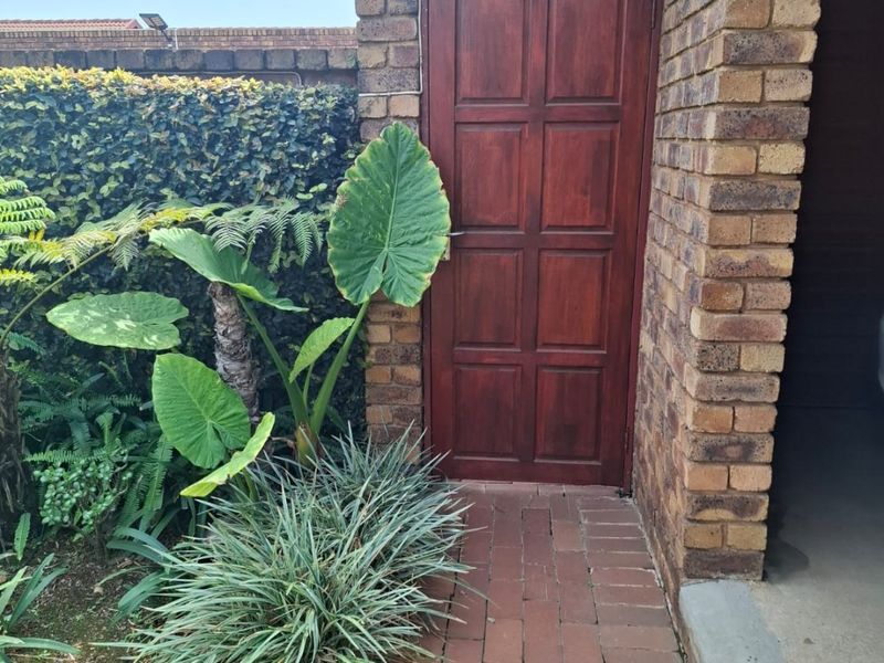 A side access area featuring a face brick wall, a solid timber door, and a brick paved pathway leading alongside the property.