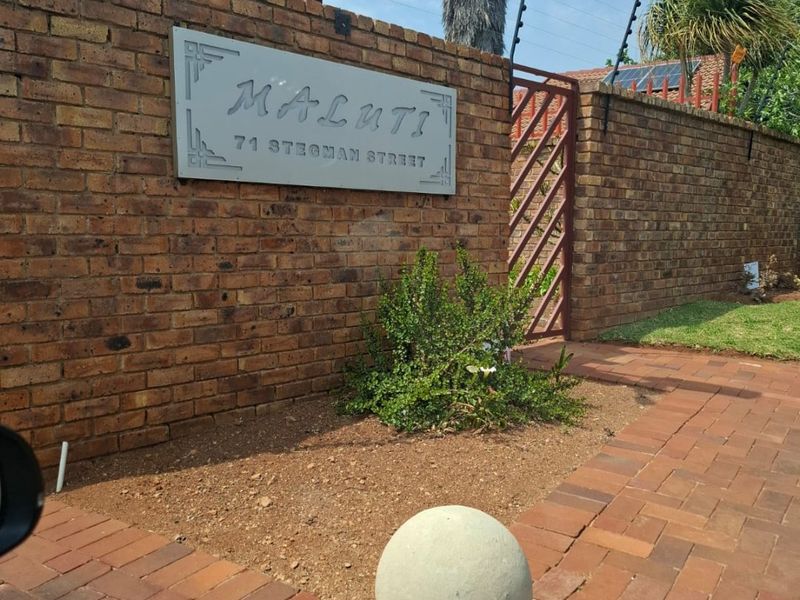 Front entrance view of the property featuring a brick boundary wall, electric fencing, and paved driveway access.