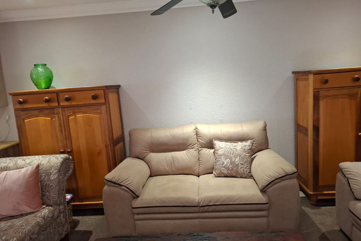 A living room area featuring a ceiling fan, recessed downlighting, and decorative coving, providing a functional space for relaxation.