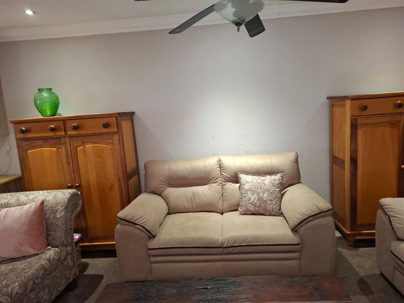 A living room area featuring a ceiling fan, recessed downlighting, and decorative coving, providing a functional space for relaxation.