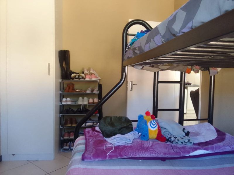 A bedroom featuring tiled flooring and a built-in wardrobe, providing functional storage space within the townhouse.