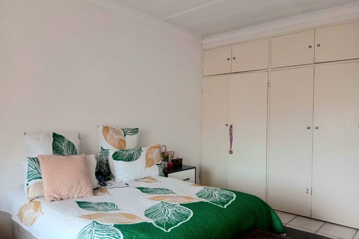 A functional bedroom featuring neutral walls, tiled flooring, and ample built-in cupboard storage space.