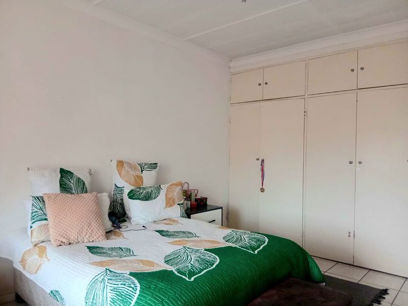A functional bedroom featuring neutral walls, tiled flooring, and ample built-in cupboard storage space.