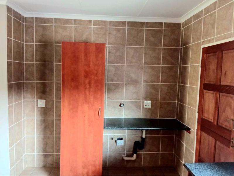A functional laundry area featuring tiled walls, a granite countertop, and dedicated plumbing connections for appliances.