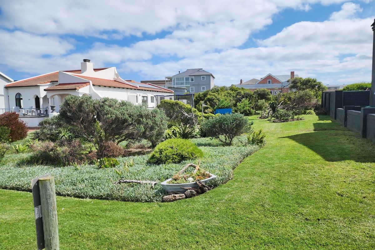 A well-maintained residential garden featuring established landscaping, lush green lawn, and surrounding boundary walls in a quiet neighborhood setting.
