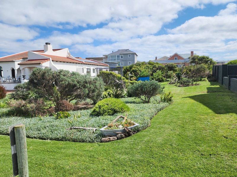 A well-maintained residential garden featuring established landscaping, lush green lawn, and surrounding boundary walls in a quiet neighborhood setting.