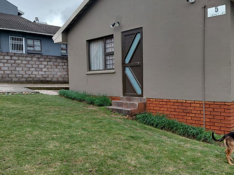 Front exterior view of the house featuring a brick plinth, security door, and well-maintained lawn area.