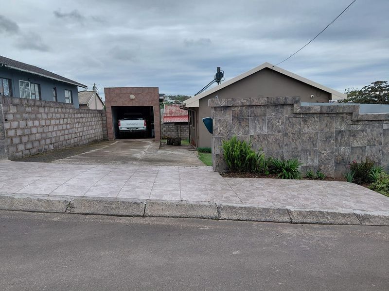 Front exterior view showing a paved driveway, single garage, and tiled boundary walling with a solar geyser installed on the roof.