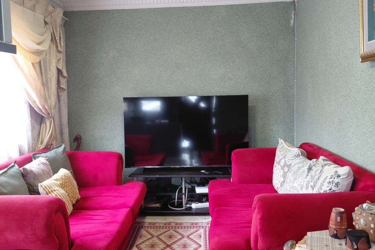 A living room featuring tiled flooring, decorative ceiling cornicing, and a central flush mount light fixture.