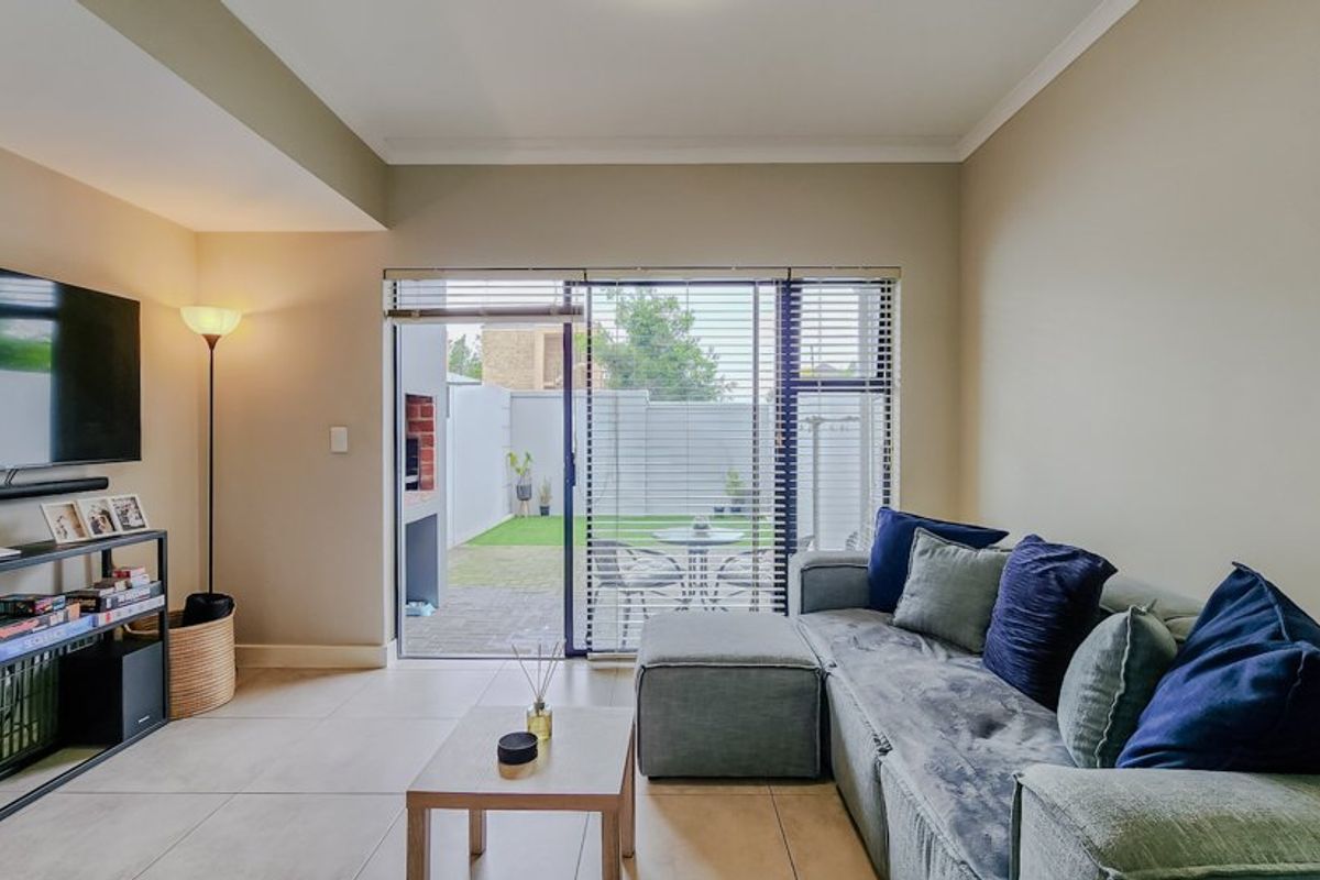 A bright living room featuring tiled flooring and a large sliding glass door that provides direct access to the outdoor patio area.