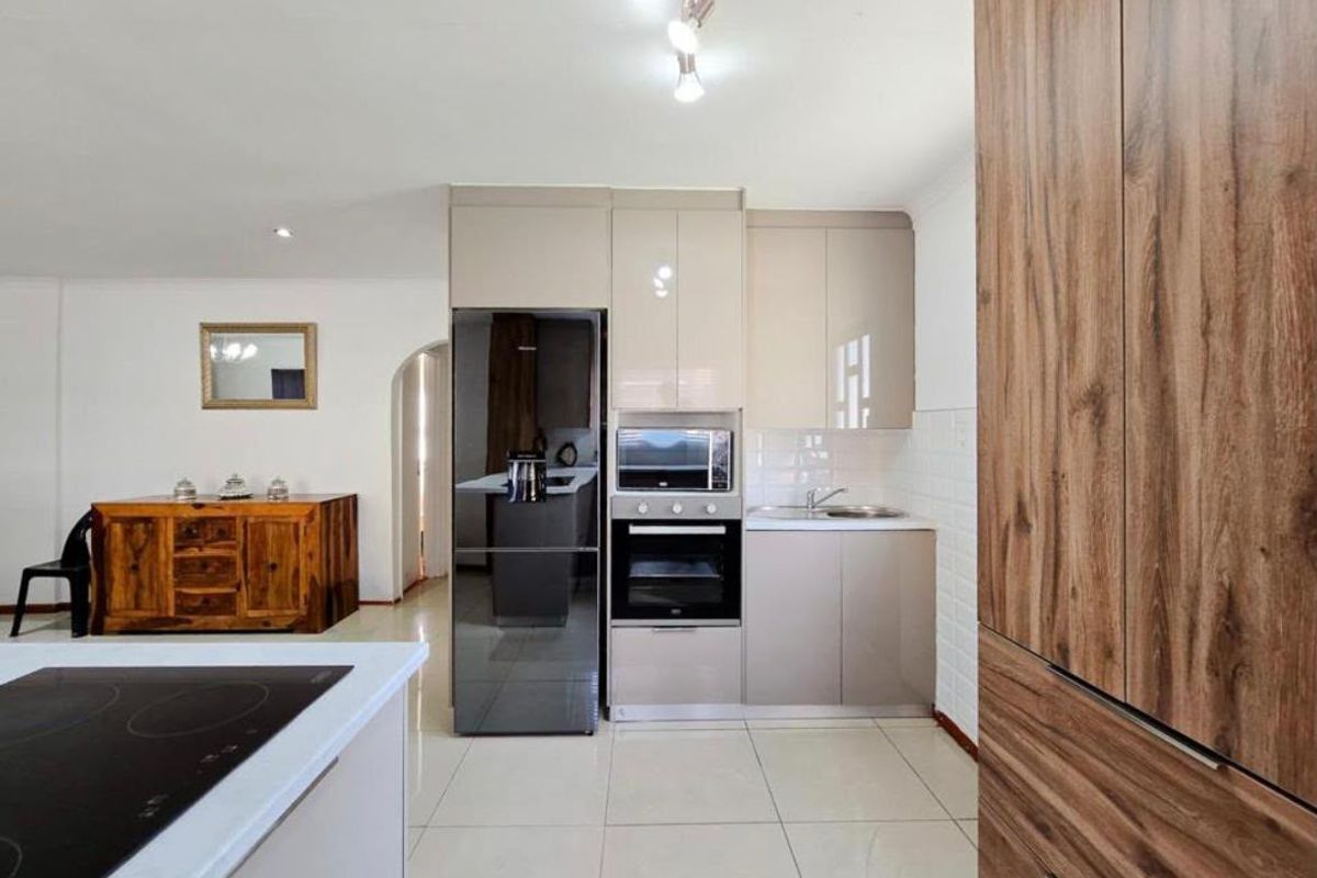 Modern kitchen featuring sleek cabinetry, built-in oven and microwave, tiled flooring, and a functional layout with integrated appliances.