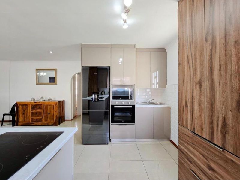 Modern kitchen featuring sleek cabinetry, built-in oven and microwave, tiled flooring, and a functional layout with integrated appliances.