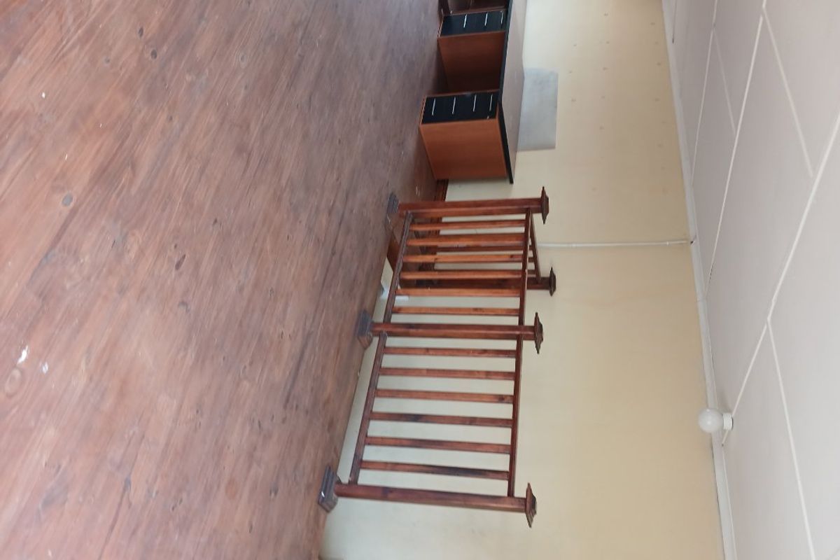 An empty room featuring wooden flooring and a wooden balustrade, requiring cosmetic updates to the walls and flooring to improve its overall condition.