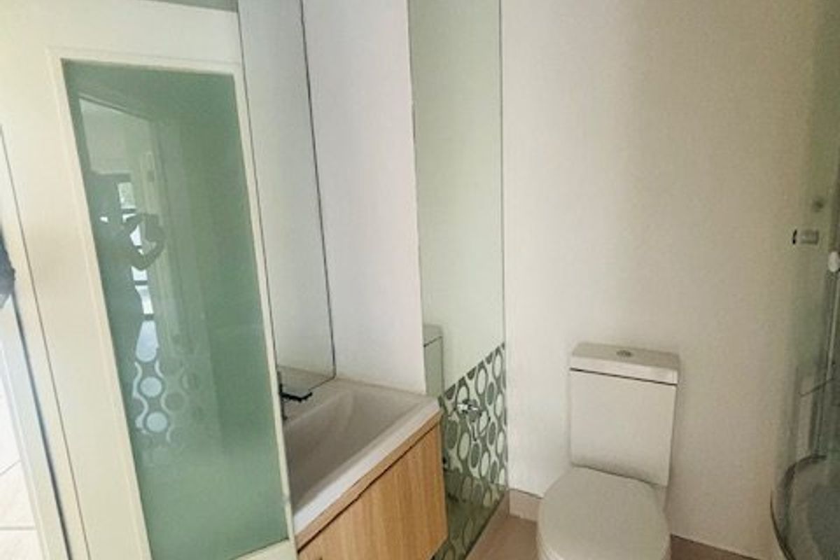A clean and functional bathroom featuring a vanity cabinet with integrated washbasin, a standard toilet, and tiled flooring with frosted glass accents.
