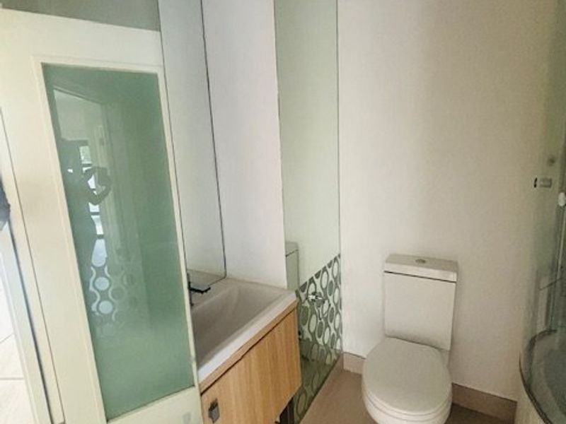 A clean and functional bathroom featuring a vanity cabinet with integrated washbasin, a standard toilet, and tiled flooring with frosted glass accents.