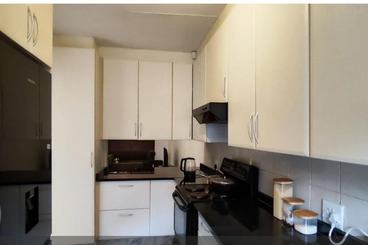 A functional kitchen featuring white cabinetry, black granite countertops, a tiled backsplash, and a built-in extractor fan.