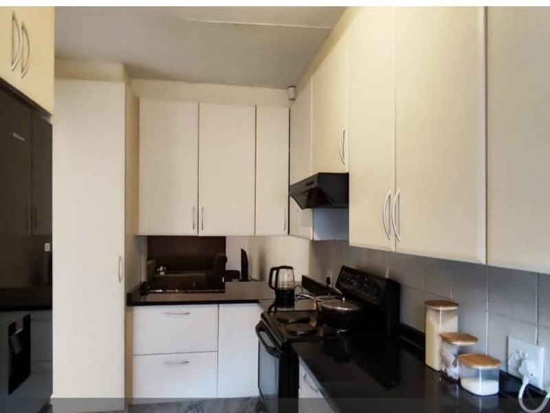 A functional kitchen featuring white cabinetry, black granite countertops, a tiled backsplash, and a built-in extractor fan.
