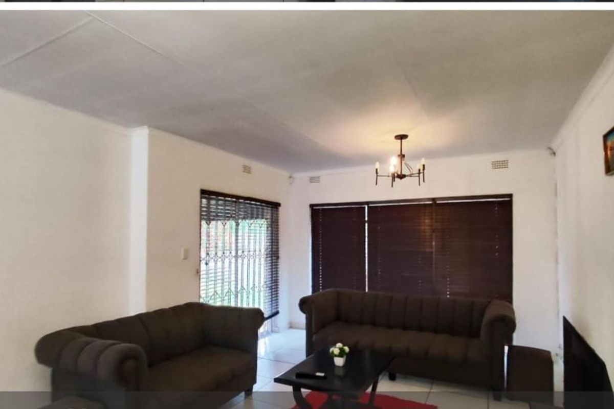 A living room featuring tiled flooring, security gates, and venetian blinds, offering a functional space with potential for cosmetic updates.